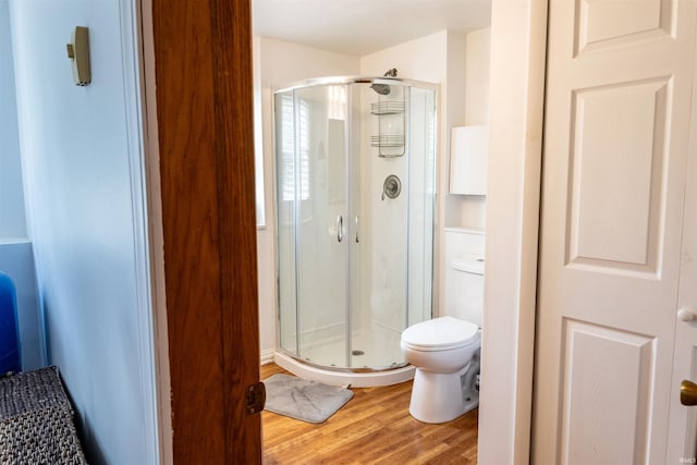 full bath featuring a shower stall, toilet, and wood finished floors