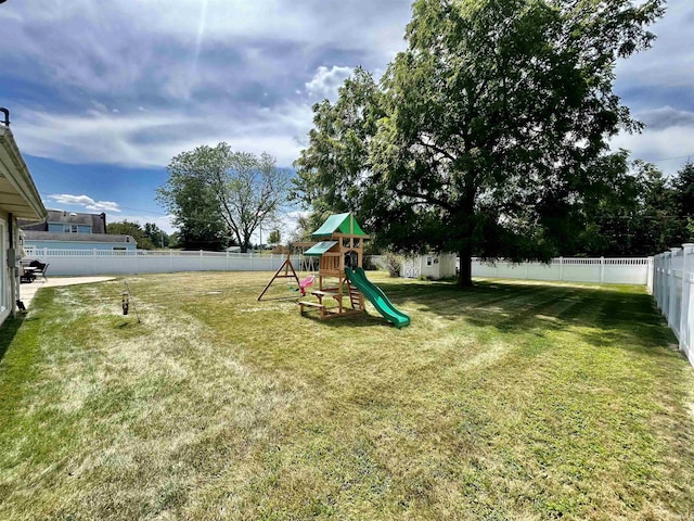 community play area with a fenced backyard and a lawn