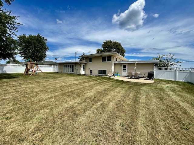 back of house featuring a yard, a fenced backyard, a playground, and a patio