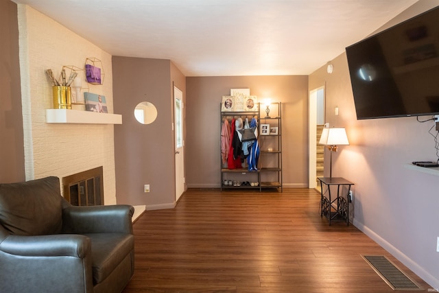 interior space with visible vents, a brick fireplace, baseboards, and wood finished floors