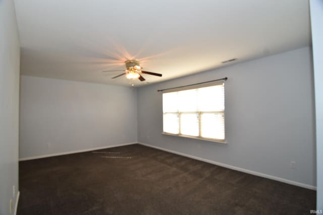 empty room featuring visible vents, baseboards, and dark colored carpet