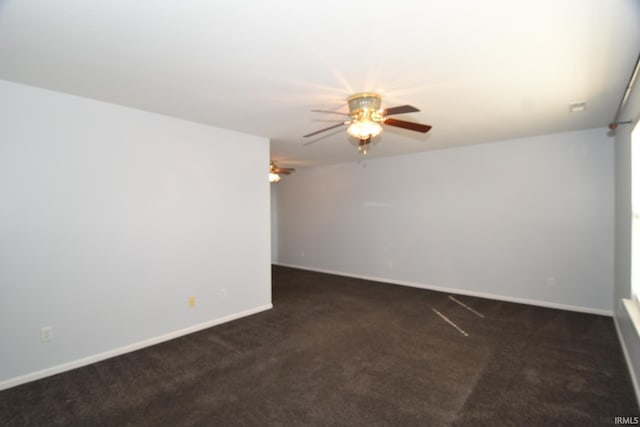 empty room with baseboards, dark carpet, and ceiling fan