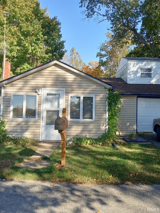 bungalow-style house featuring a garage and a front lawn