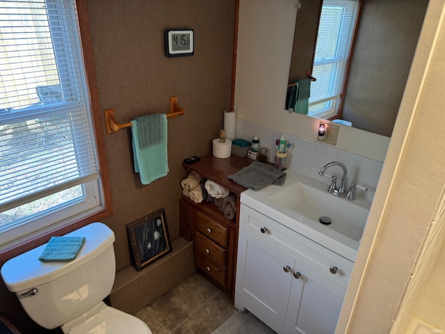 bathroom with backsplash, plenty of natural light, toilet, and vanity