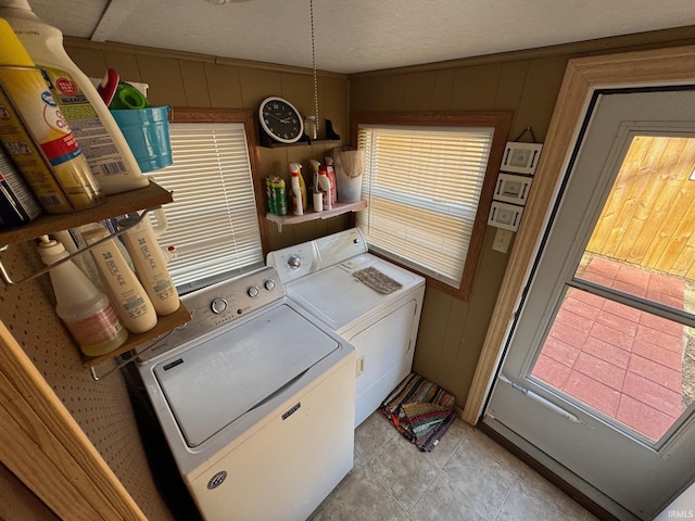 clothes washing area with washing machine and clothes dryer, laundry area, plenty of natural light, and light tile patterned floors