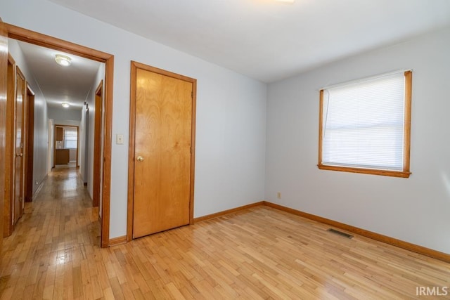 unfurnished bedroom featuring visible vents, light wood-style flooring, baseboards, and multiple windows