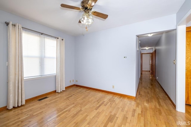 spare room with visible vents, light wood-style flooring, baseboards, and ceiling fan