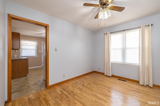 spare room featuring visible vents, ceiling fan, baseboards, and light wood-style floors