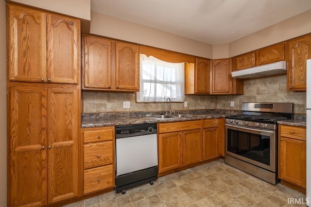 kitchen featuring white dishwasher, a sink, under cabinet range hood, stainless steel gas range oven, and dark countertops