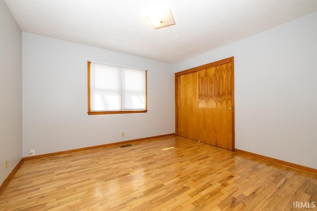 unfurnished bedroom with a closet, baseboards, and light wood-style flooring