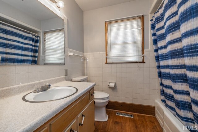 bathroom with a wealth of natural light, toilet, wood finished floors, and vanity