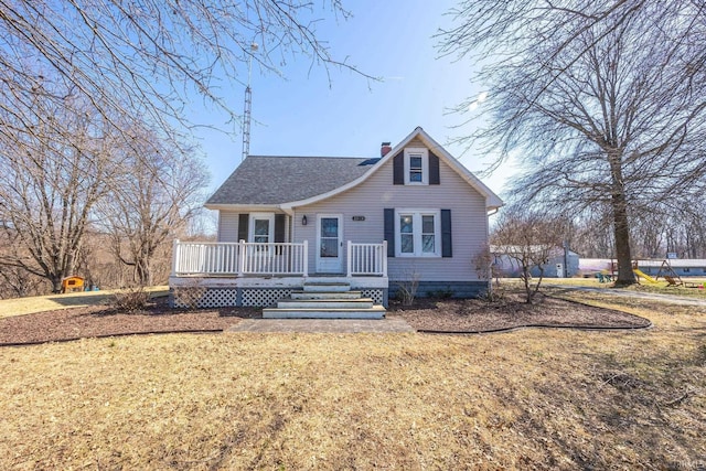 bungalow-style house featuring a front lawn, a deck, a chimney, and a shingled roof