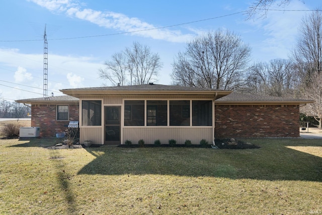 view of front of property featuring a front lawn, brick siding, and a sunroom