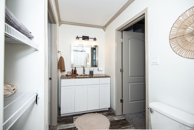 bathroom featuring wood finished floors, toilet, ornamental molding, and vanity