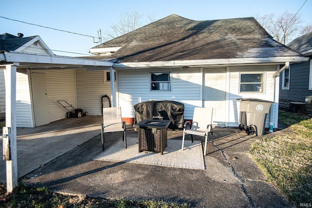 back of house featuring a patio and roof with shingles