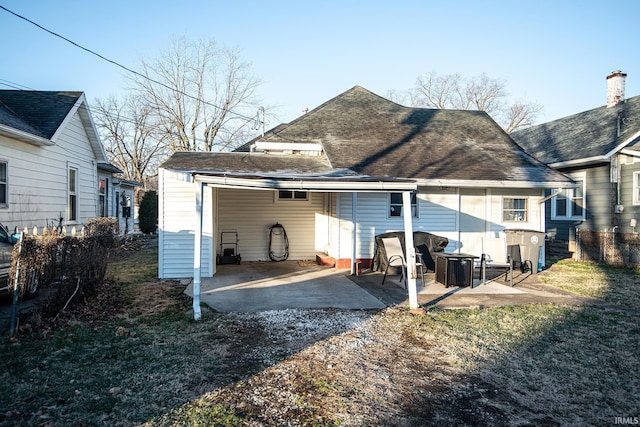 rear view of house with a patio and roof with shingles