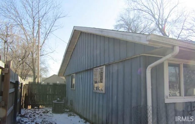 view of side of property with board and batten siding, central AC, and fence