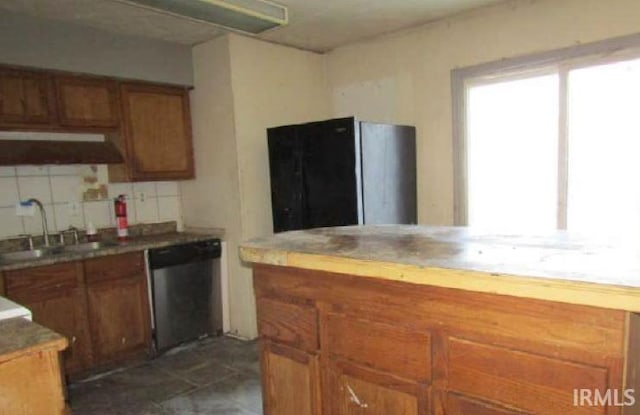 kitchen featuring a sink, decorative backsplash, brown cabinets, and dishwasher