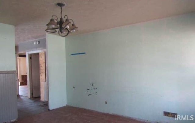 spare room featuring a notable chandelier and wainscoting