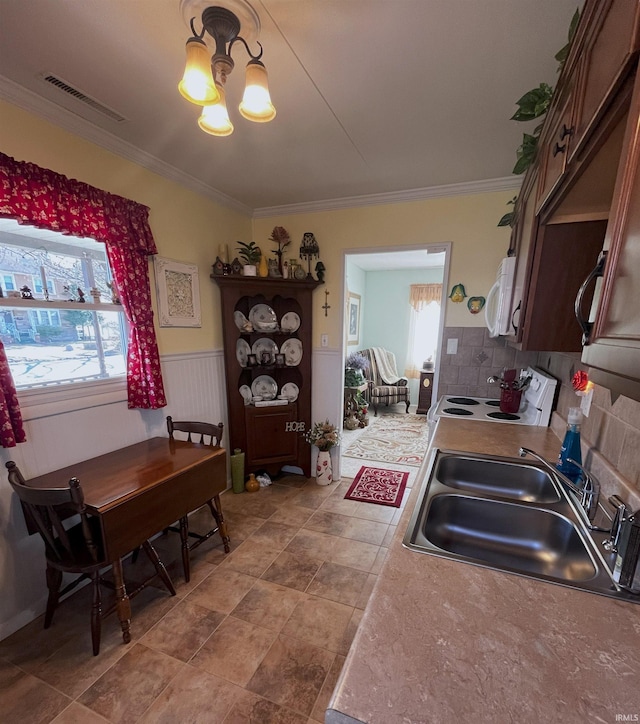 kitchen with visible vents, a wainscoted wall, a sink, white appliances, and an inviting chandelier