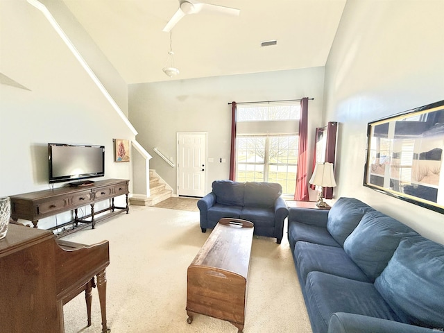 carpeted living area featuring visible vents, high vaulted ceiling, stairs, and ceiling fan