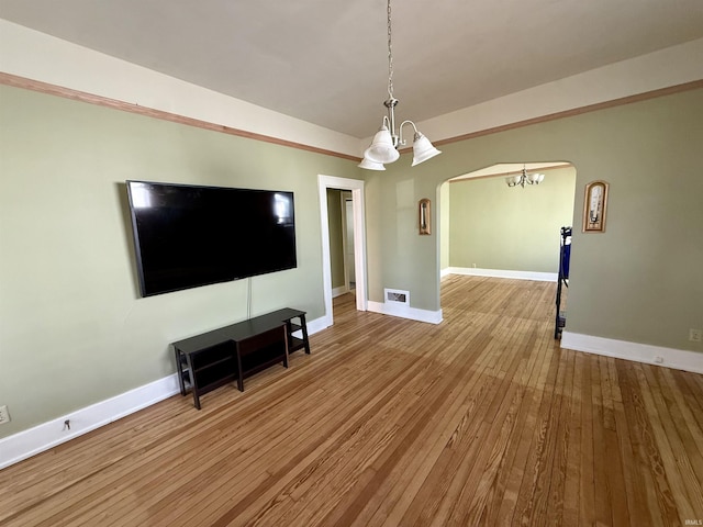 living area featuring hardwood / wood-style flooring, baseboards, arched walkways, and a chandelier