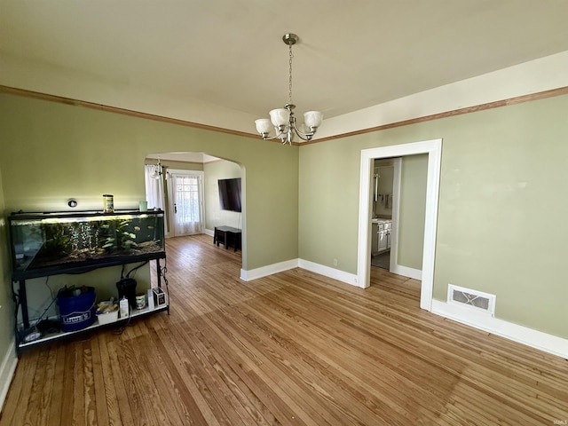 dining room with visible vents, baseboards, a chandelier, wood finished floors, and arched walkways