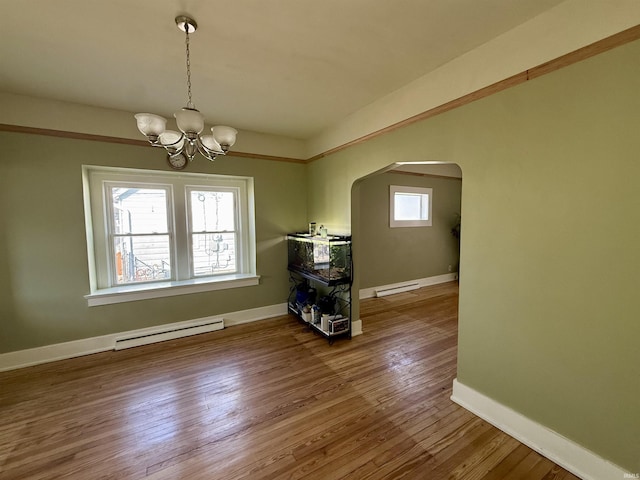 unfurnished dining area with arched walkways, a baseboard heating unit, a wealth of natural light, and wood-type flooring