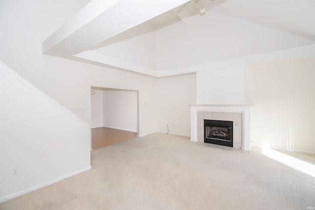 unfurnished living room featuring baseboards, a fireplace, high vaulted ceiling, and carpet