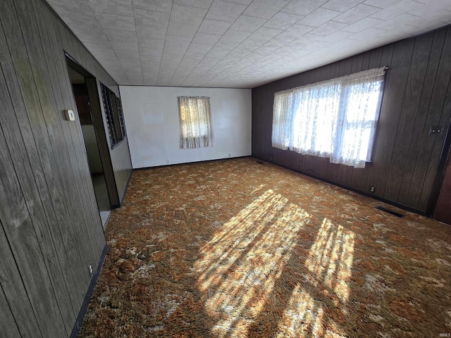 spare room featuring visible vents and wood walls