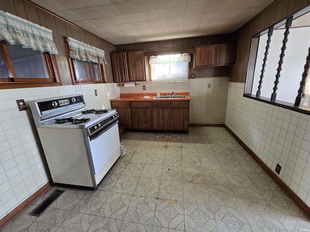 kitchen with light floors, visible vents, a sink, light countertops, and white gas range