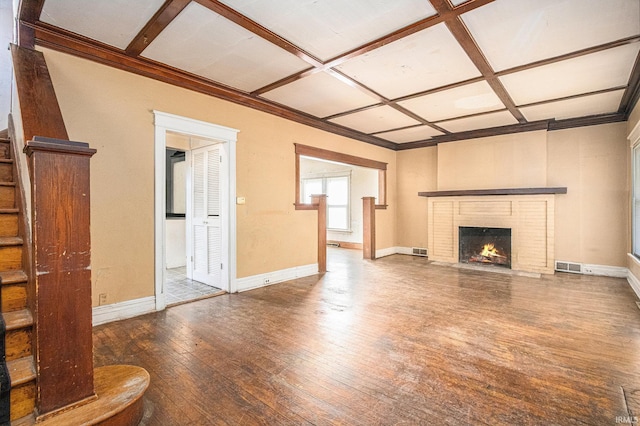 unfurnished living room with visible vents, hardwood / wood-style flooring, coffered ceiling, baseboards, and a brick fireplace