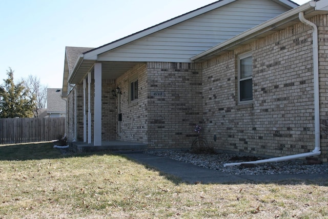 view of home's exterior with a yard, fence, and brick siding