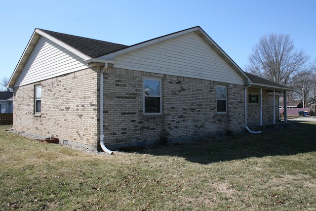 view of side of home featuring a lawn and brick siding