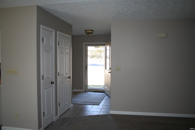 entryway featuring light tile patterned flooring, light colored carpet, baseboards, and a textured ceiling