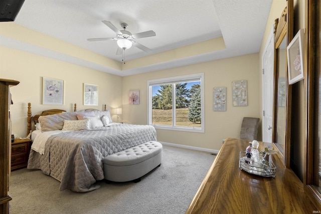 bedroom with a raised ceiling, carpet flooring, baseboards, and ceiling fan