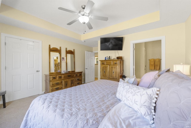 carpeted bedroom featuring a raised ceiling and a ceiling fan