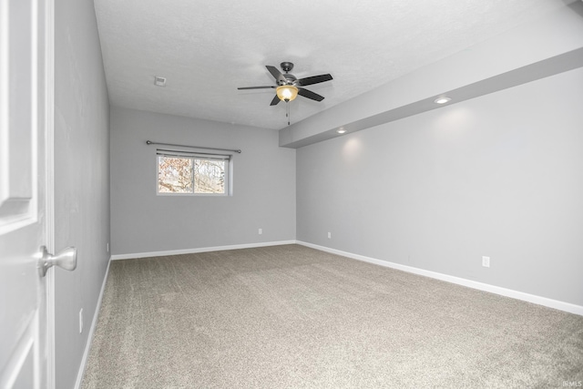 carpeted empty room featuring baseboards, a textured ceiling, and a ceiling fan