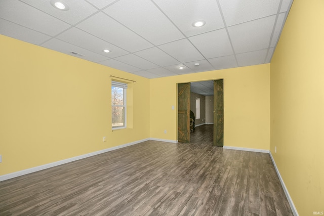 spare room with dark wood-style floors, recessed lighting, a paneled ceiling, and baseboards