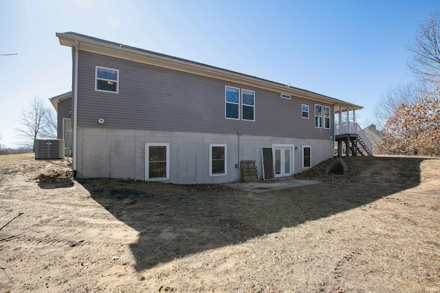 rear view of property with stairway, french doors, and central AC