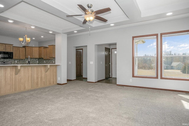 kitchen featuring light countertops, black microwave, a kitchen breakfast bar, light colored carpet, and backsplash