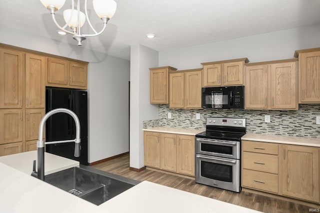 kitchen featuring a sink, backsplash, black appliances, and dark wood finished floors