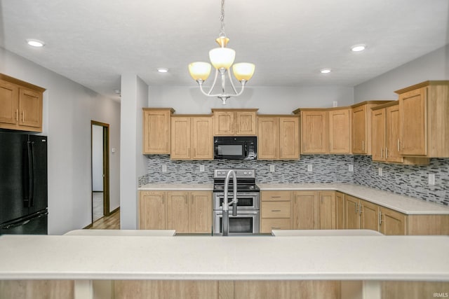 kitchen featuring pendant lighting, backsplash, black appliances, and light countertops