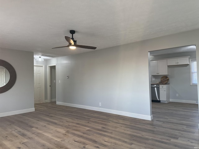 unfurnished living room with dark wood finished floors, a ceiling fan, and baseboards