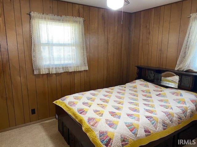 bedroom featuring light carpet and wooden walls