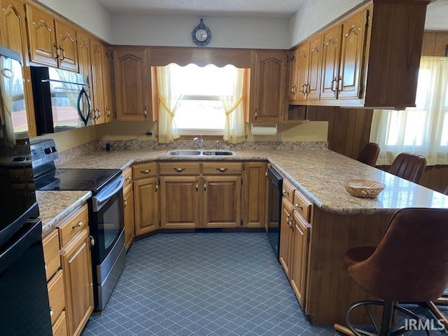 kitchen featuring a sink, a kitchen bar, plenty of natural light, and black appliances