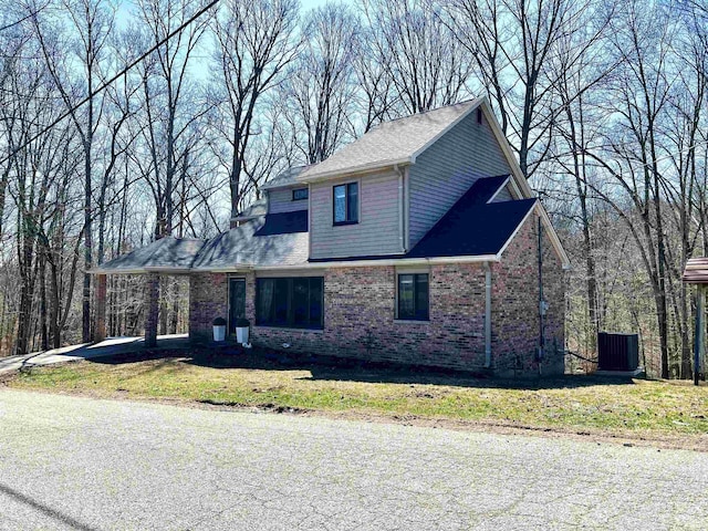 view of front of property featuring cooling unit, brick siding, and a front yard