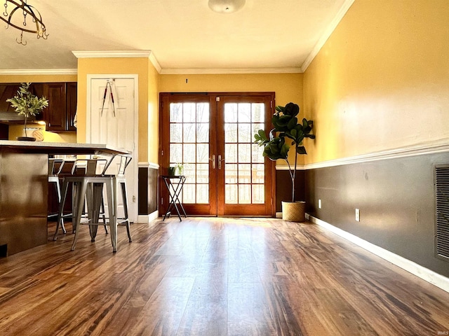 doorway to outside featuring french doors, baseboards, wood finished floors, and ornamental molding