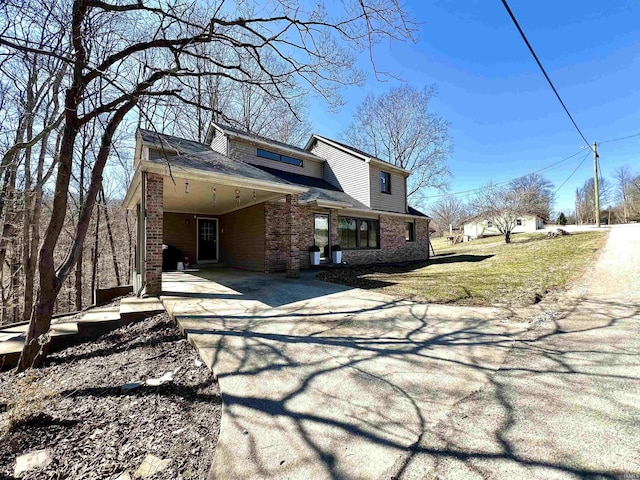 exterior space featuring brick siding, an attached carport, driveway, and a lawn