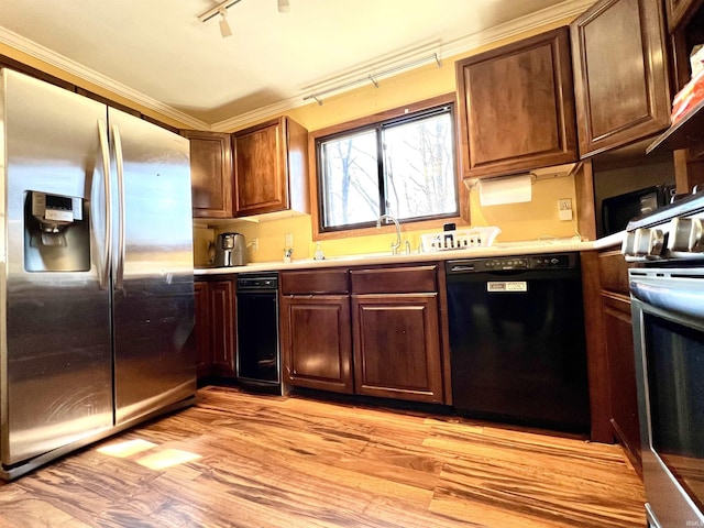 kitchen with light wood finished floors, stainless steel appliances, light countertops, and a sink